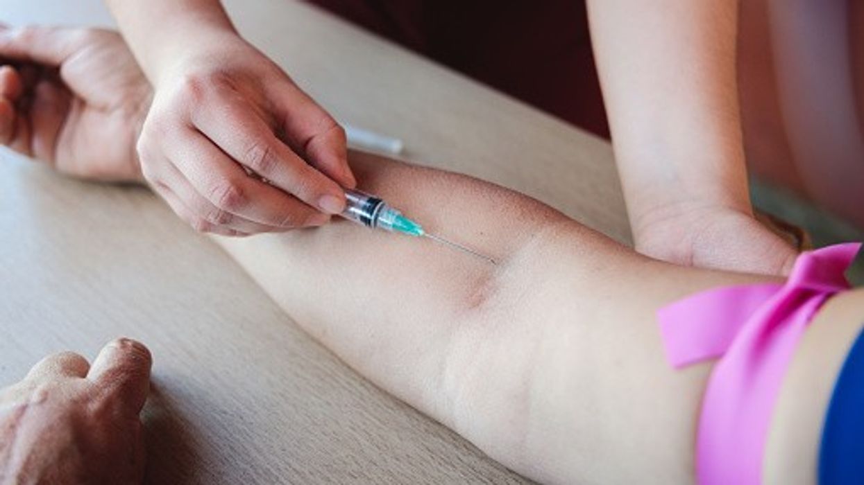 Healthcare worker inserting IV into arm.