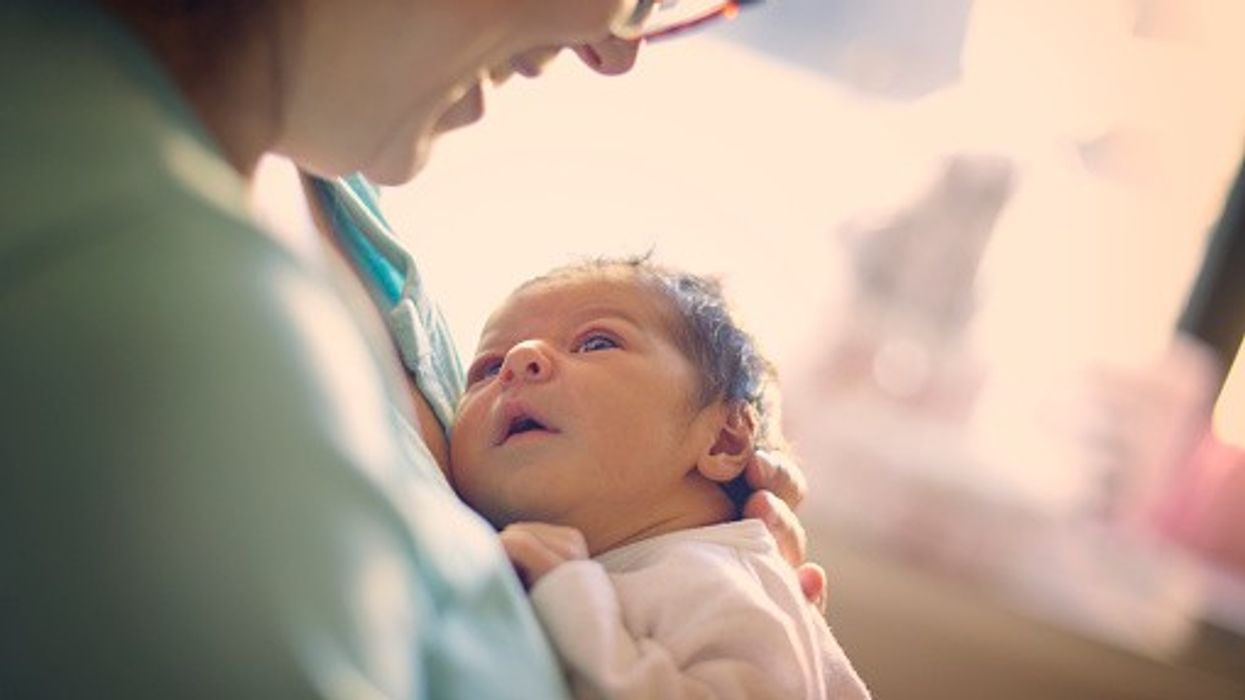 Mother holding newborn baby during early postnatal care in NHS maternity setting