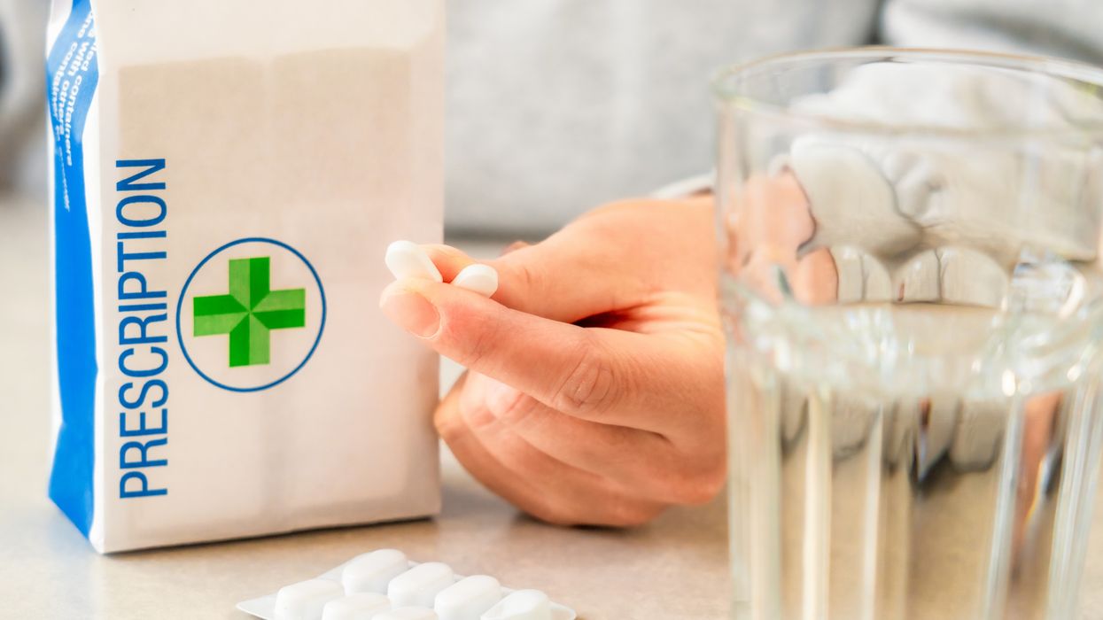 Pharmacist handing medicine to patient, NHS prescription cost freeze debate