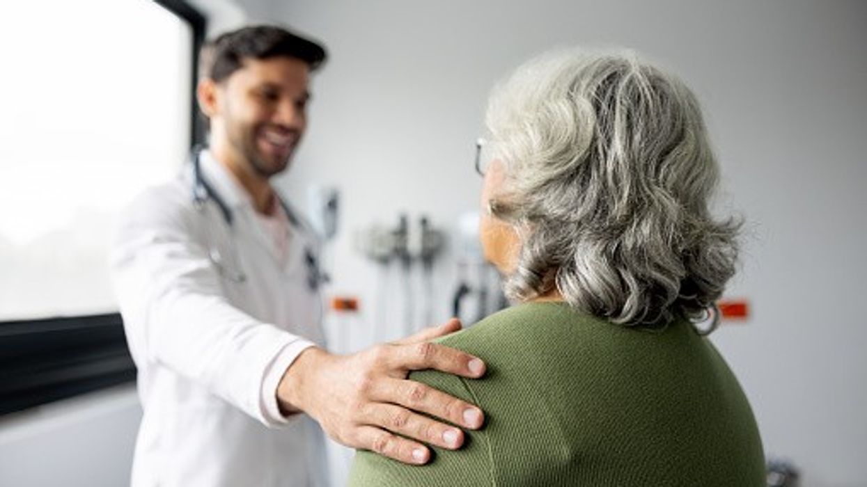 Smiling GP reassures elderly patient during NHS consultation in clinic